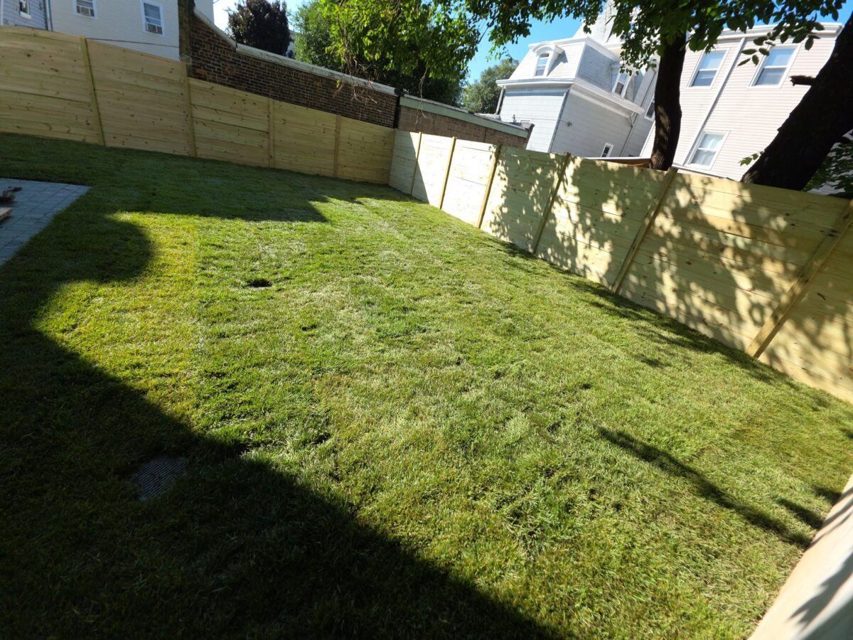 Completed Long Island backyard sod installation showing fresh turf inside a fenced residential yard.
